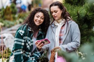 Two girls outside smiling and holding a phone